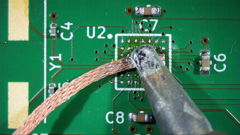 A soldering iron and desoldering braid being used to remove solder from a BGA footprint